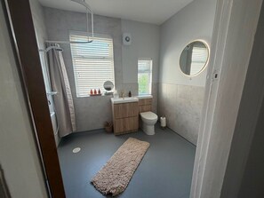Ein Badezimmer mit Dusche, Toilette, Waschbecken und Spiegel.