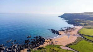 A coastal landscape with a beach, rocky shoreline, and green fields. - Seaside Retreat Cottage in Carrowmenagh (Carrowmenagh)