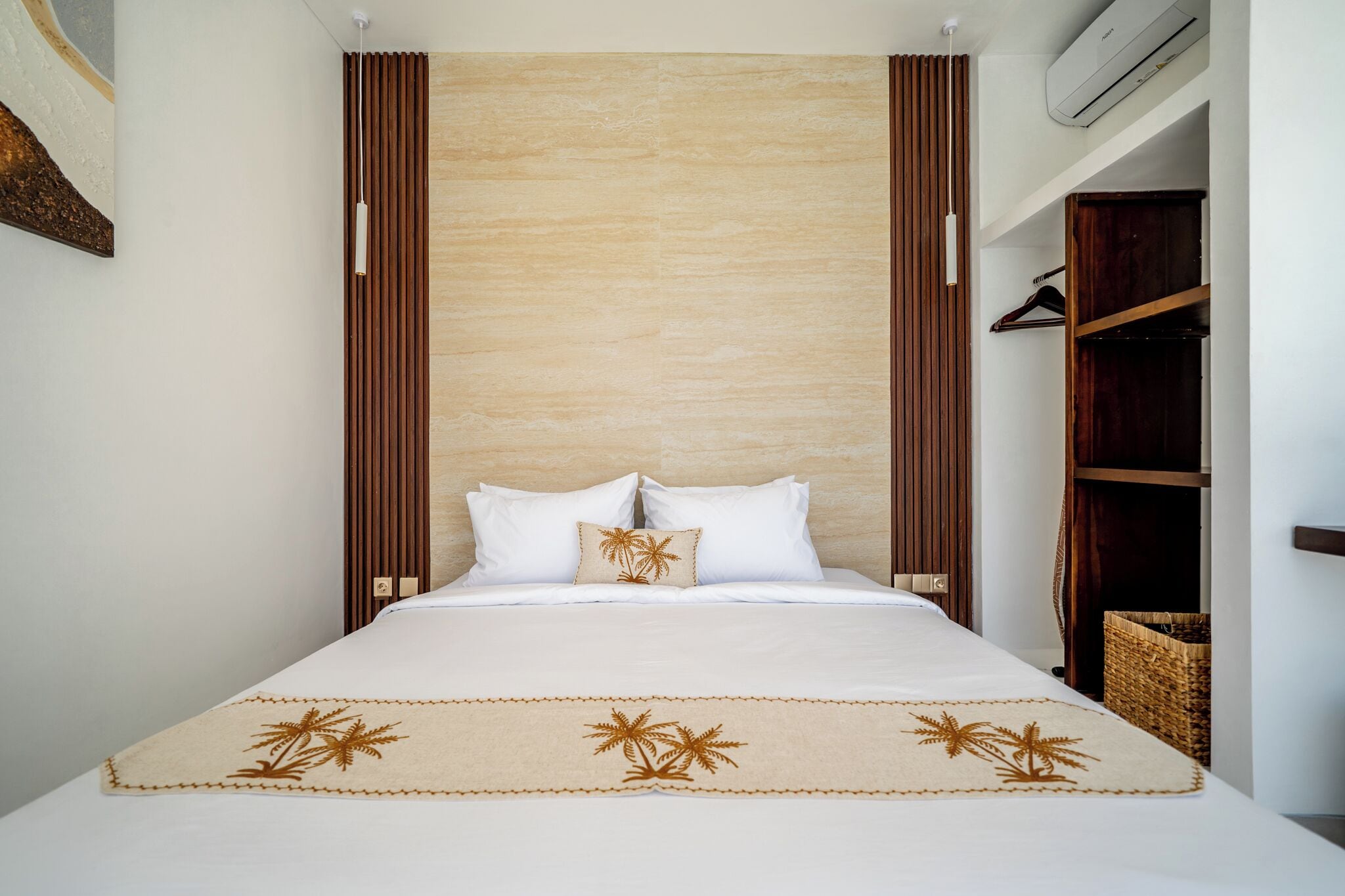 A hotel room with a bed, a wooden headboard, a wall-mounted air conditioner, and a wardrobe.