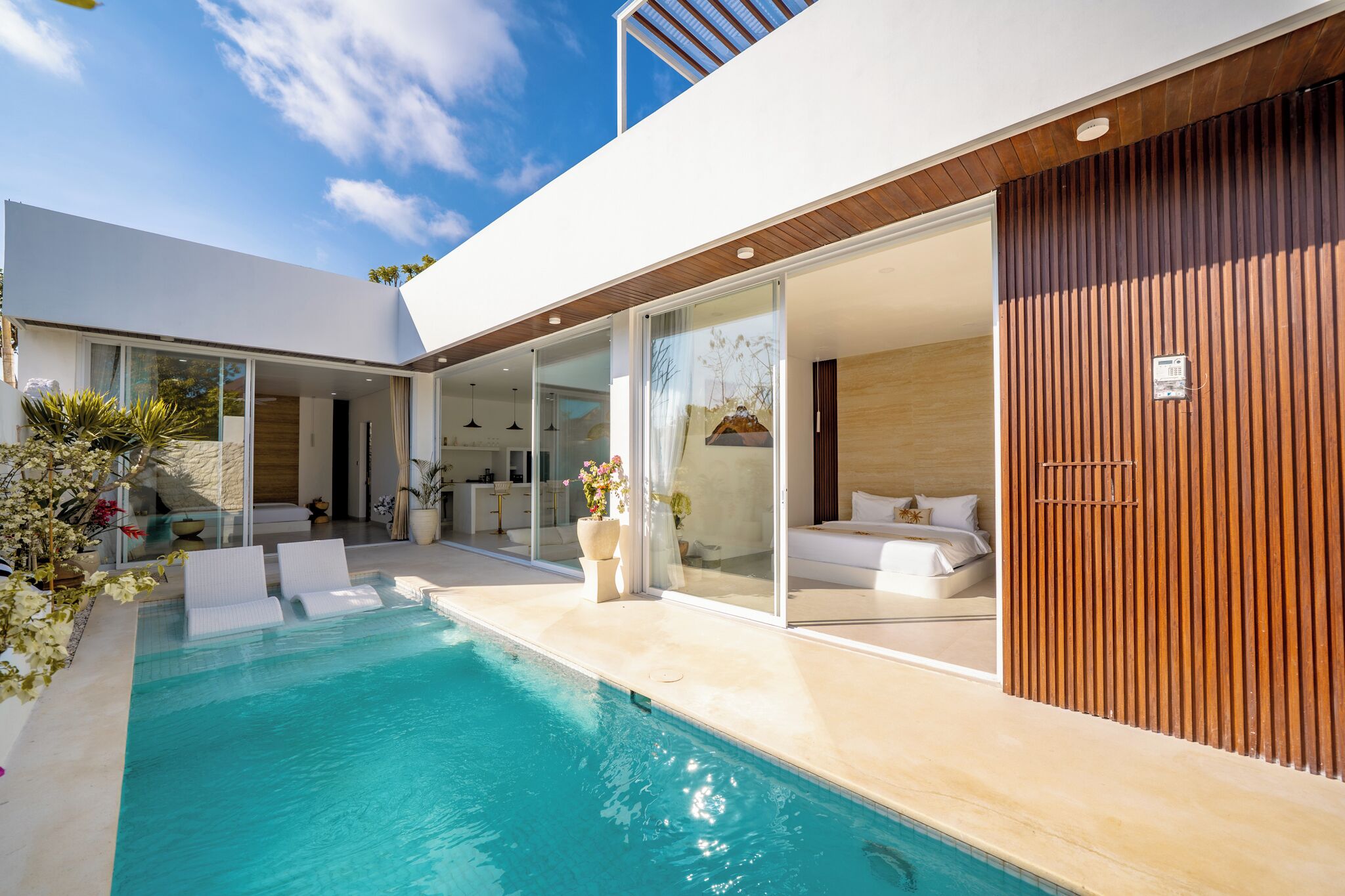 Ein modernes Haus mit Schwimmbad, einem Schlafzimmer mit großem Bett und einer Küchenzeile.