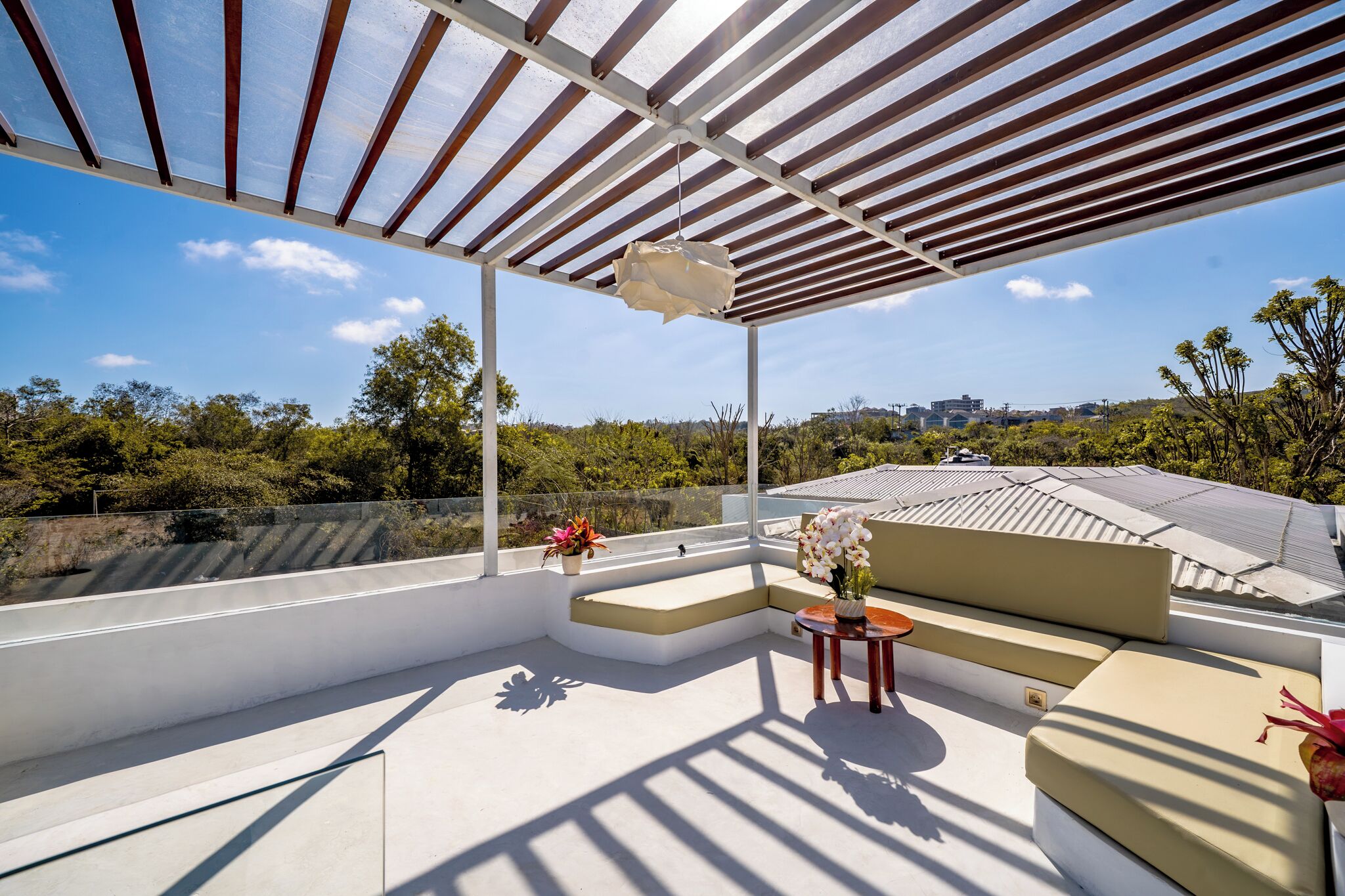 Una terraza en la azotea con pérgola, zona de estar y plantas en macetas.