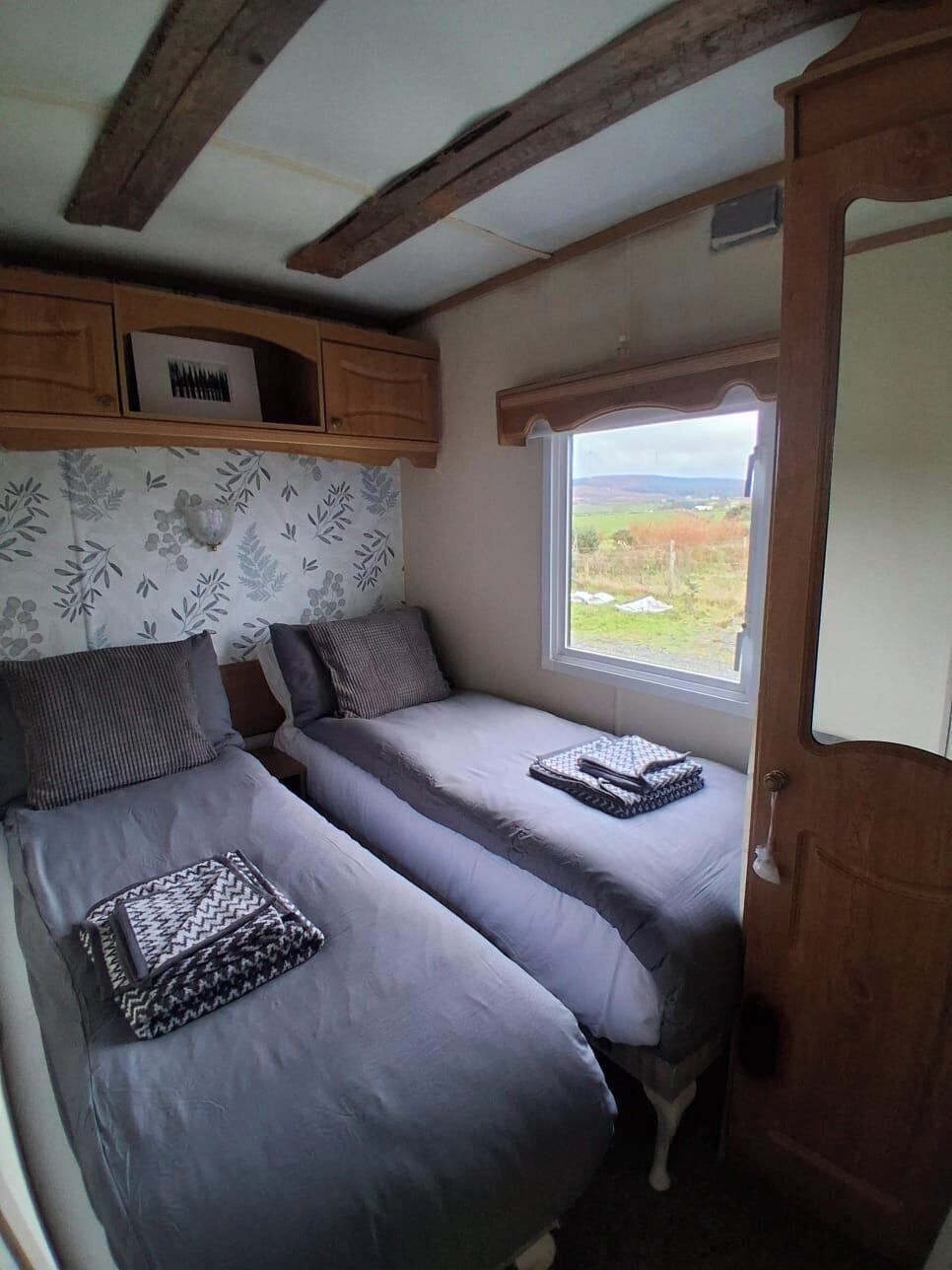 Une chambre de taille modeste, avec deux lits, une fenêtre donnant sur un beau paysage et un plafond en bois.