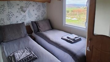 Ein kleiner Raum mit zwei Betten, einem Fenster mit Blick und einer Holzbalkendecke.