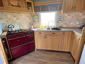 A kitchen with wooden cabinets, a gas stove, and a window above the sink.