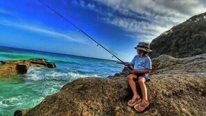 A person fishing on a rocky outcrop by the sea. - Cozy Carrowmenagh Cabin Retreat (Culdaff)