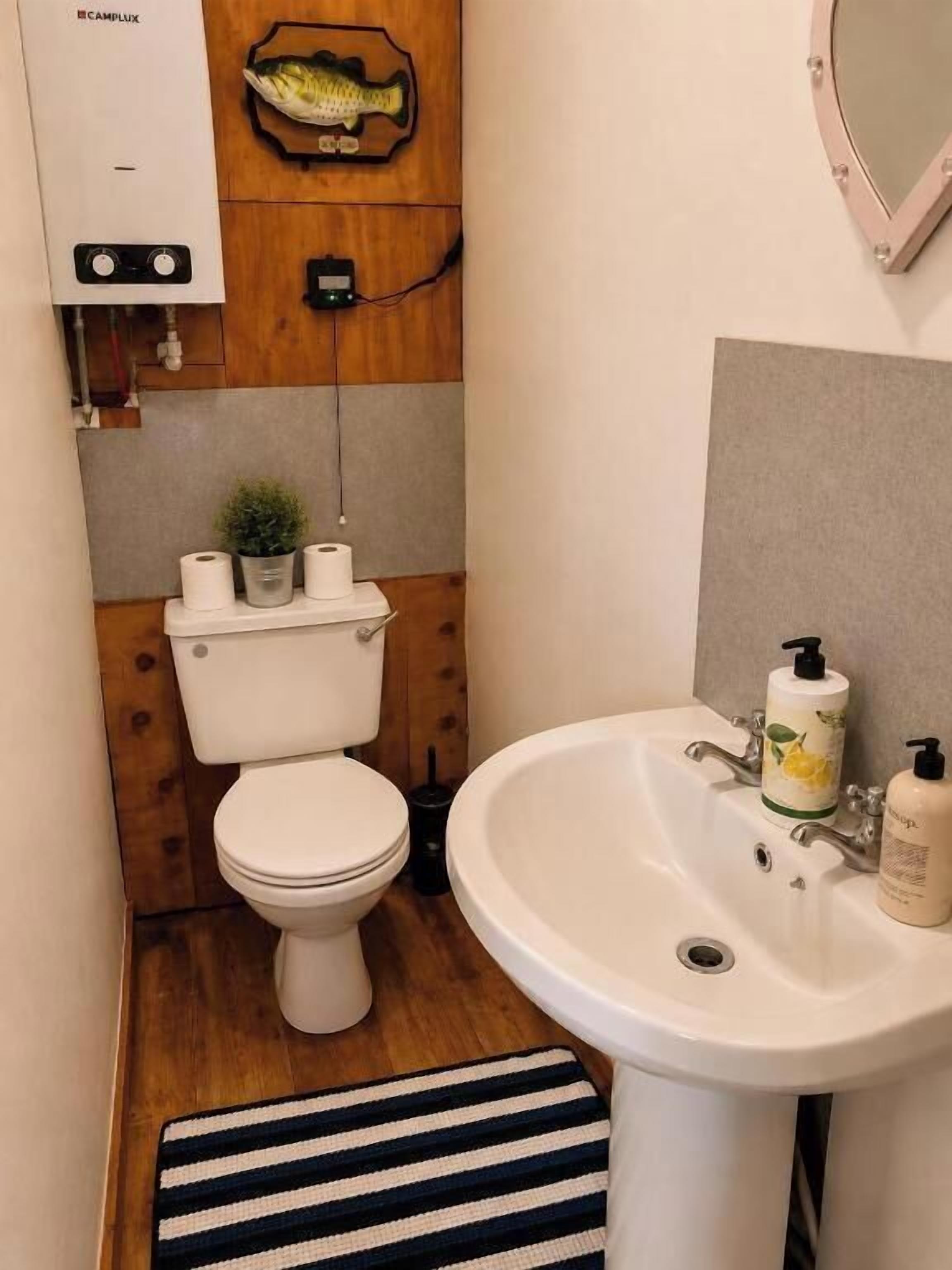 A small bathroom with a toilet, sink, and a wooden wall with a fish decoration.
