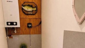 A small bathroom with a toilet, sink, and a wooden wall with a fish decoration. - Cottage Sleeps 4 with Parking and Sea Views (Carrowmenagh)