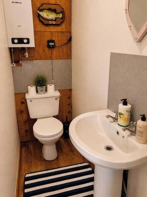 Ein kleines Badezimmer mit Toilette, Waschbecken und einer Holzwand mit einer Fischdekoration.