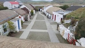 Ein Dorf mit reetgedeckten Häusern, einem zentralen Weg und einem Gewässer im Hintergrund.