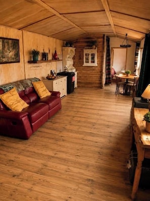 Ein gemütliches Cabin-Interieur mit Holzboden, einer roten Ledersofa, einem Esstisch und einer Küchenzeile.