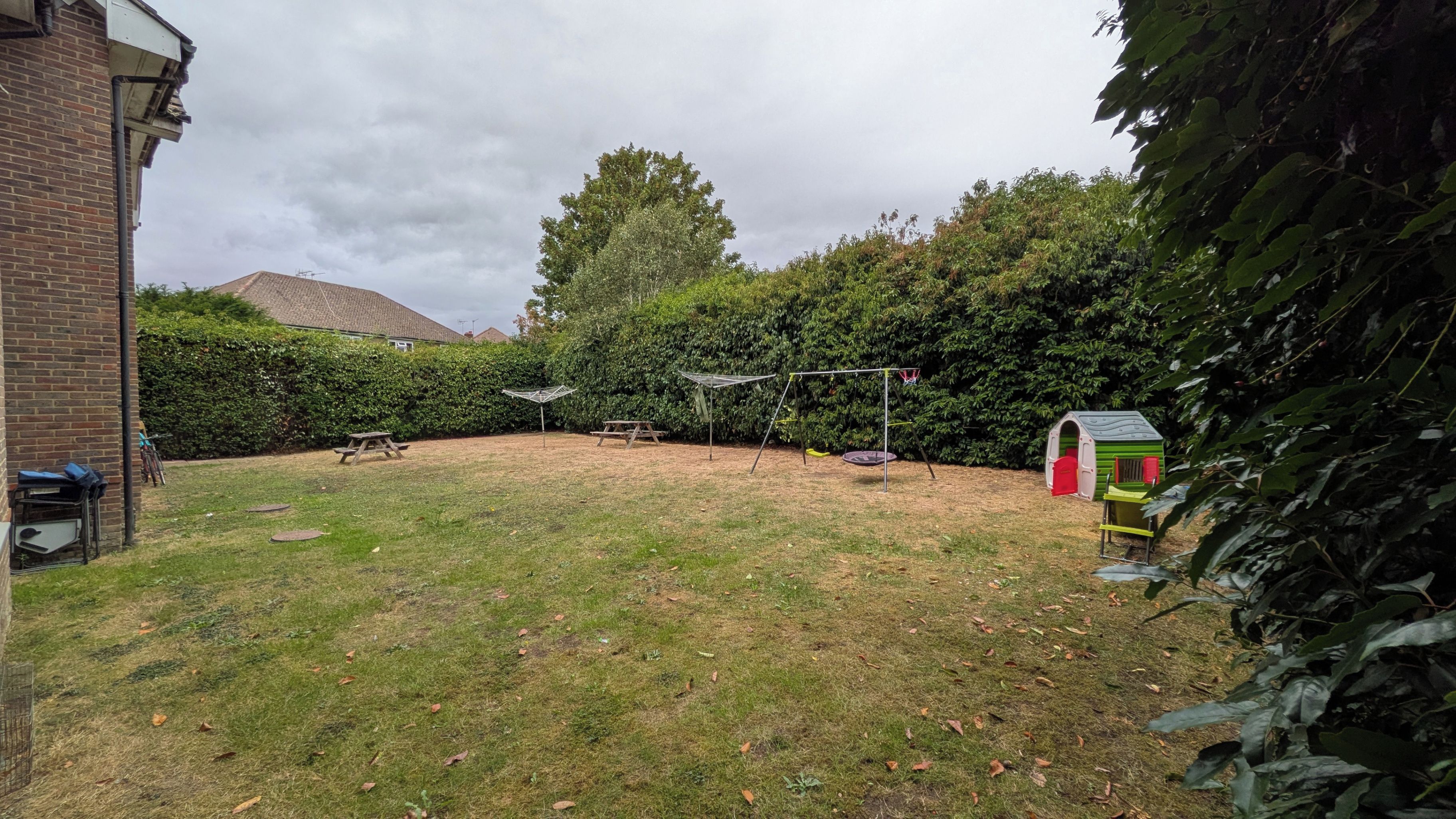 Ein Garten mit Spielbereich, einschließlich Schaukel und einer kleinen Spielhütte.