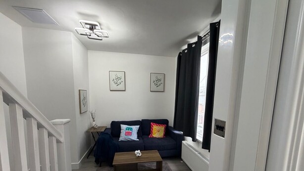 Een woonkamer met een bank, salontafel en een trap.