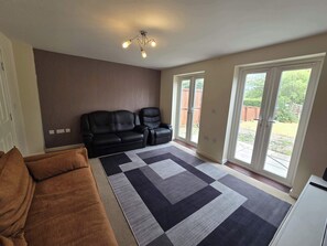A living room with a sectional sofa, a patterned rug, and a ceiling light fixture.