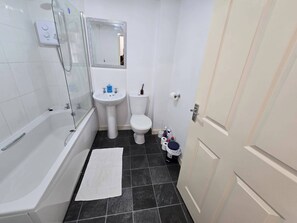 A bathroom with a bathtub, sink, toilet, and a mirror.