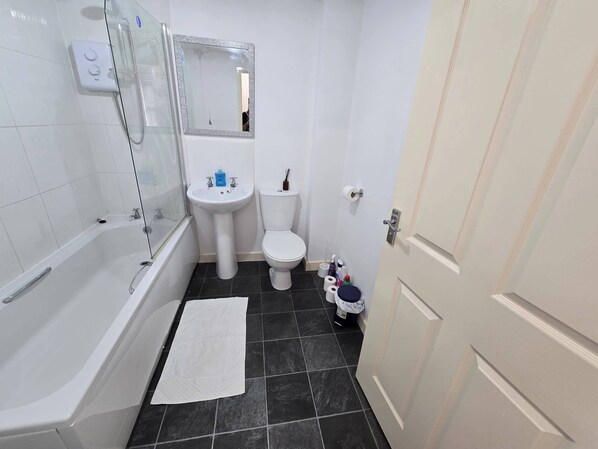 A bathroom with a bathtub, sink, toilet, and a mirror.