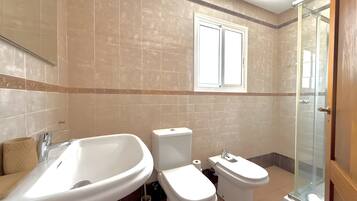 Een badkamer met een bad, toilet en douche.
