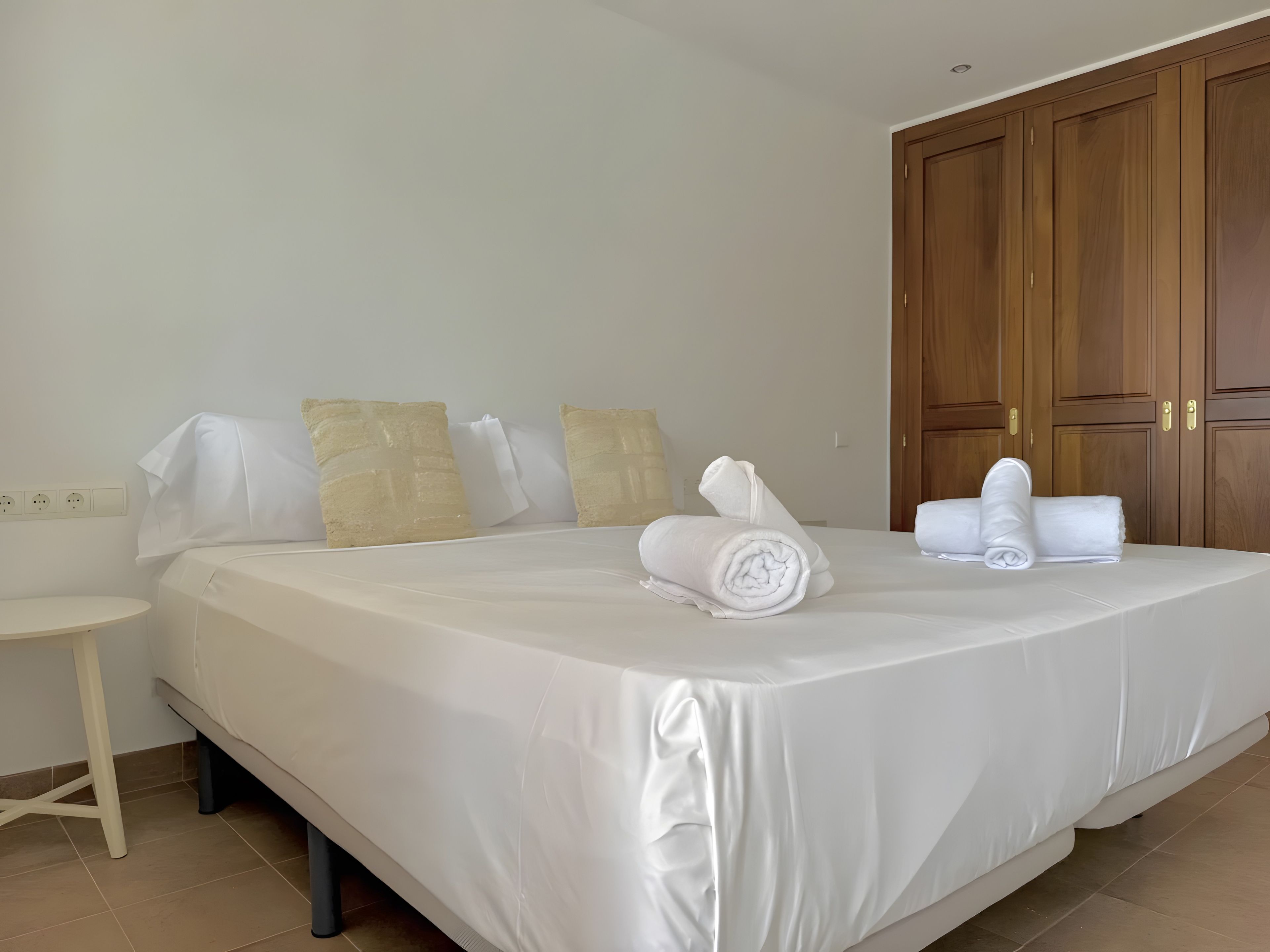 Ein Hotelzimmer mit einem großen Bett, einem Nachttisch und Holzschränken.