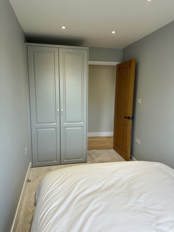 A bedroom with a bed, a grey wardrobe, and a wooden door.