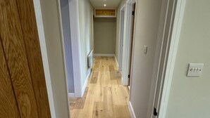 A hallway with wooden flooring, white walls, and recessed lighting. - Apartment Sleeps 4 with Parking (London)