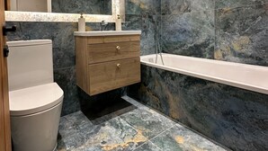 A modern bathroom with a toilet, vanity, and bathtub. - Apartment Sleeps 4 with Parking (London)