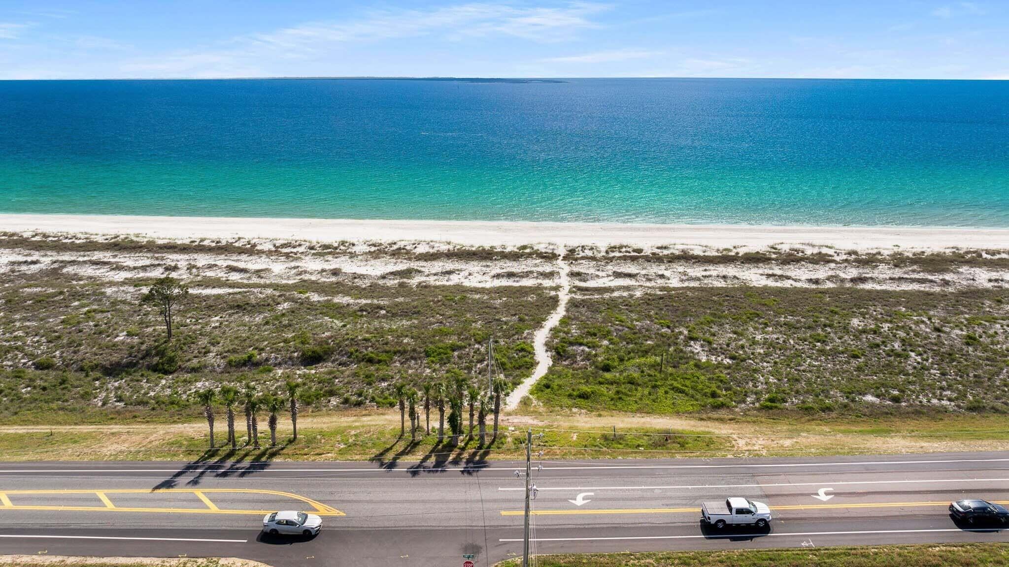 A coastal road with a clear view of the ocean and beach.