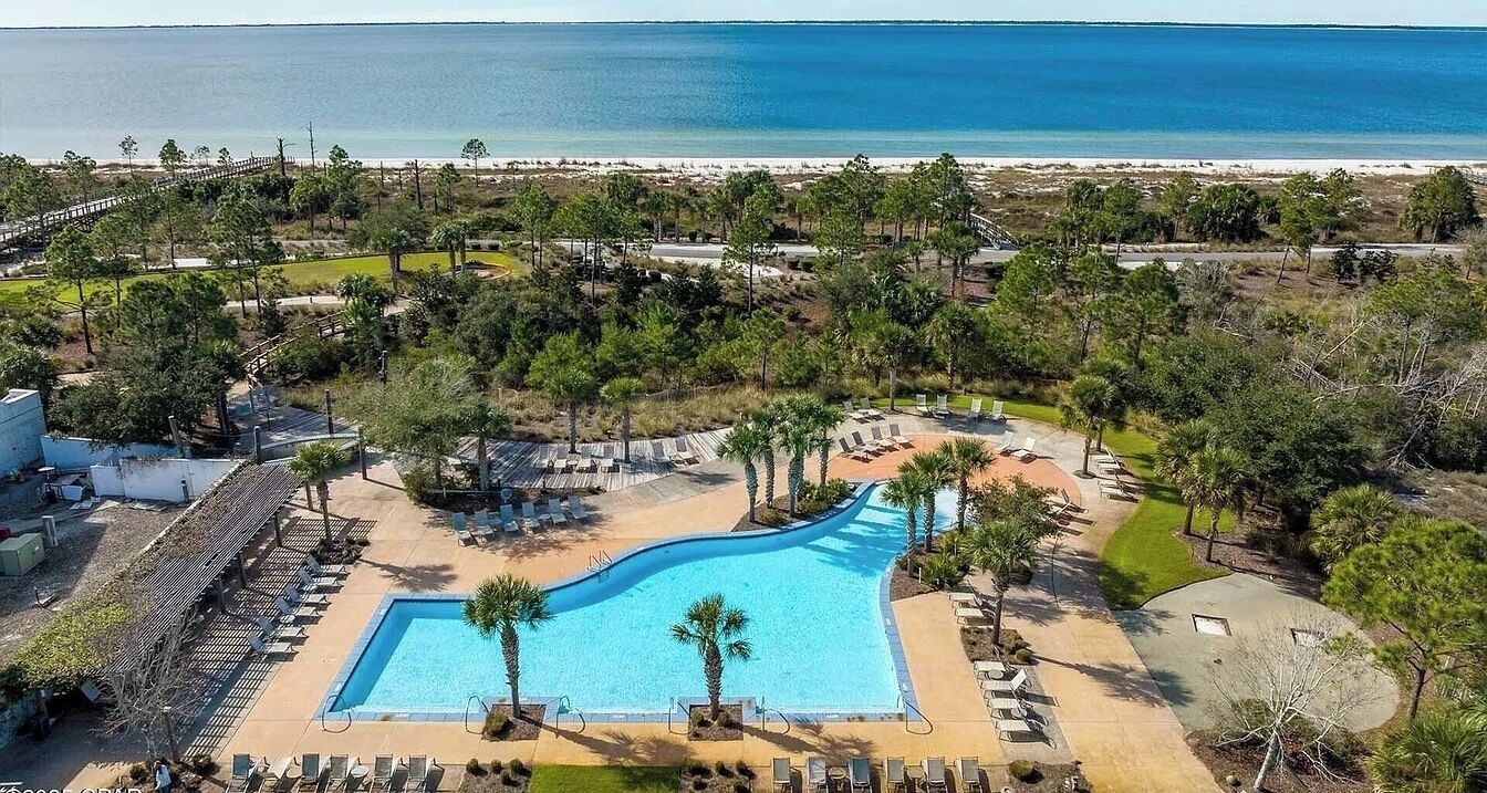 A resort with a swimming pool, lounge chairs, and a view of the beach.