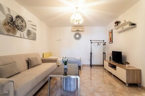 Ein stilvolles Wohnzimmer mit einer Couch, einem Couchtisch, einem Fernseher und Dekorationselementen.