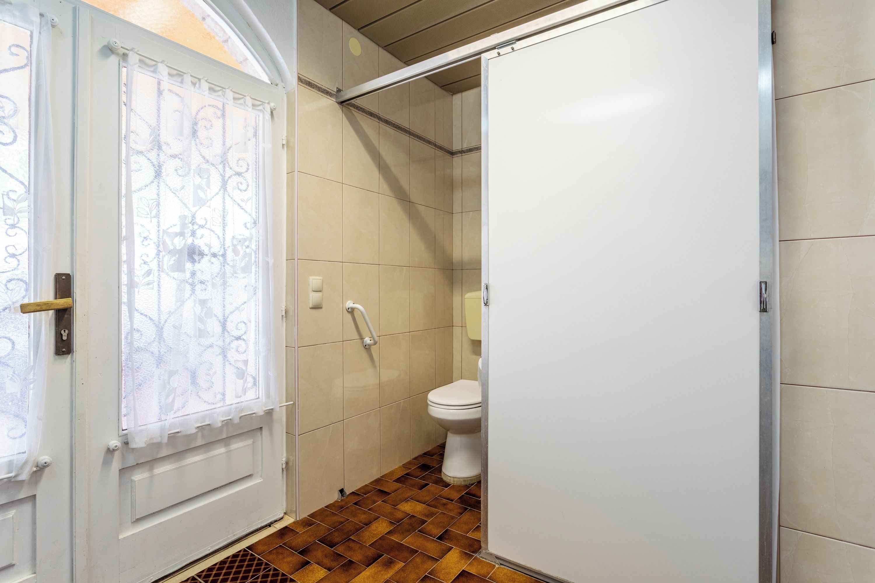 Ein Badezimmer mit Toilette, Duschbereich und einer Tür mit Dekor.