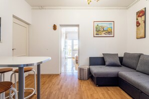 A modern living room with a grey sofa, a round table with chairs, and a painting on the wall. - A3 - Spacious apt w pool, terrace and sea view (Dugi Rat)