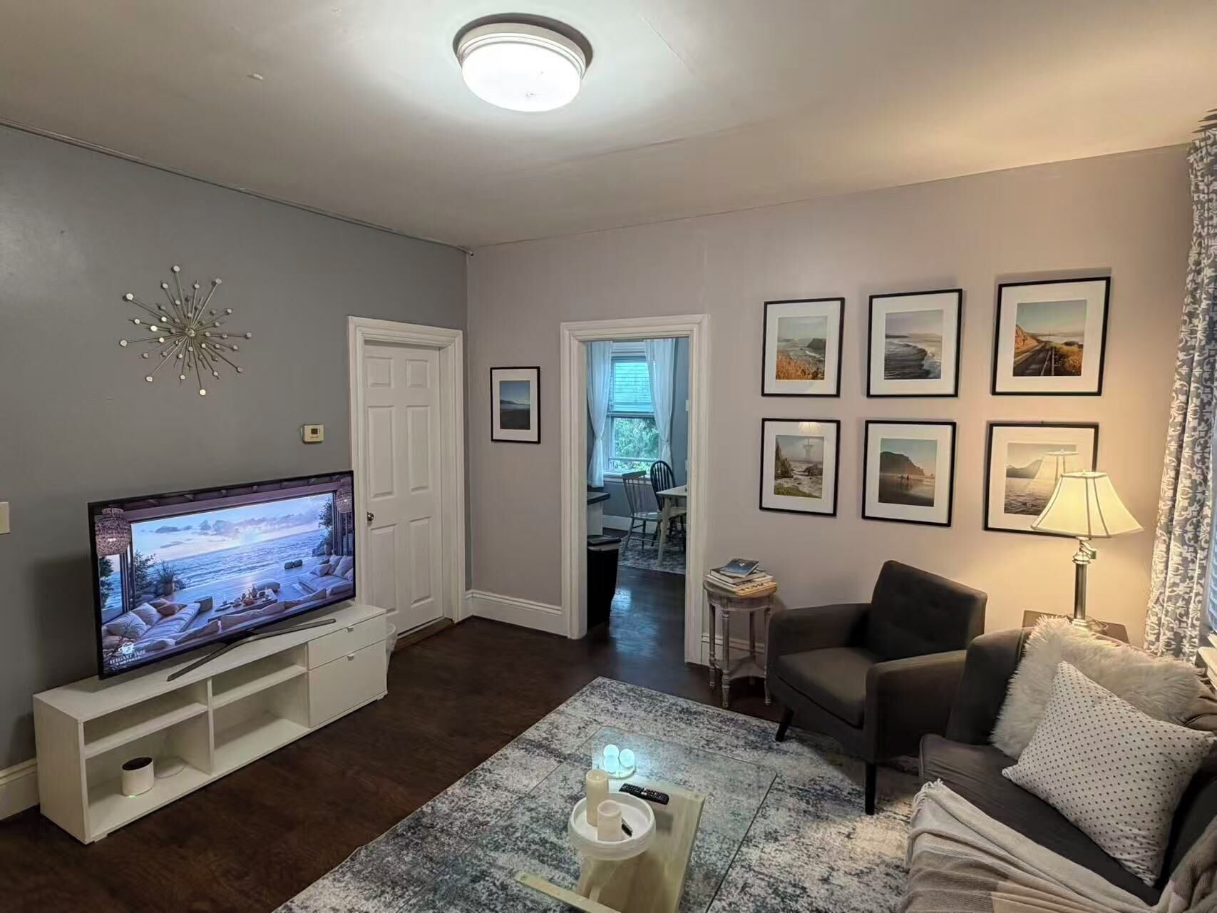 A living room with a flat-screen TV, a sofa, a coffee table, and a lamp.