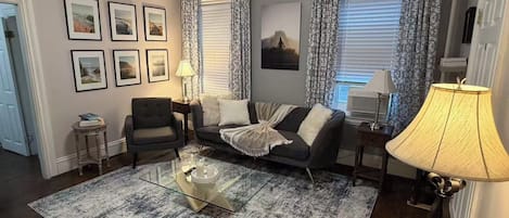 Una sala de estar con sofá, sillón, mesa de centro y lámpara.