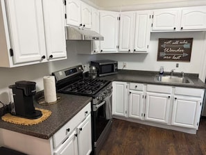A kitchen with white cabinets, a stove, a microwave, and a sink. - Close to Brown & RISD lovely 4-bedroom apartment (Providence)