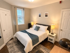 A bedroom with a bed, bedside lamps, a window with curtains, and a door. - Close to Brown & RISD lovely 4-bedroom apartment (Providence)