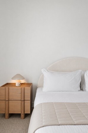 A bedroom with a bed, a bedside table with a lamp, and a carpeted floor. - Balcony 2-Bed Residence Near Albert Park (St Kilda)
