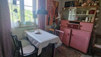 Un comedor con una mesa, sillas, un radio y un refrigerador rosa.