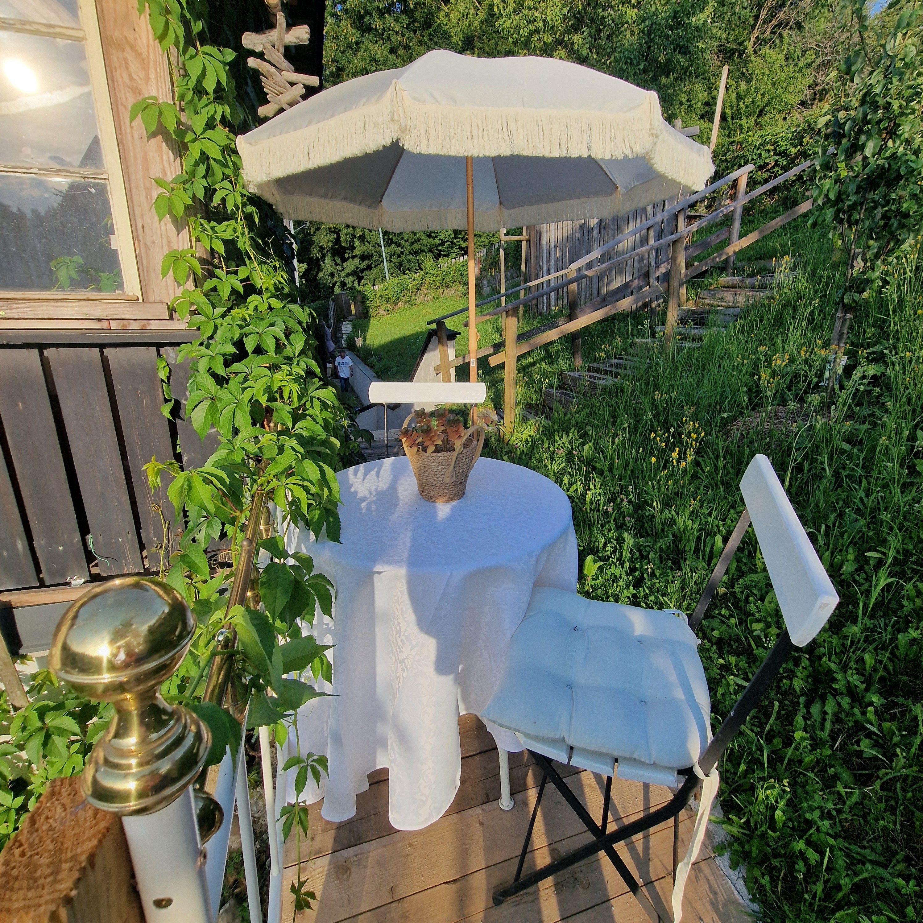 Um terraço com mesa, cadeiras, um guarda-sol e uma cerca de madeira.