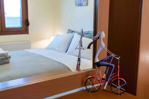 Ein Schlafzimmer mit einem Bett, Kissen, einem Nachttisch und einem Spiegel, der eine Person auf einem Fahrrad reflektiert.