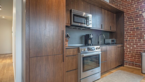 Una cocina moderna con armarios de madera, electrodomésticos de acero inoxidable y una pared de ladrillo.