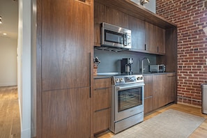 Una cocina moderna con armarios de madera, electrodomésticos de acero inoxidable y una pared de ladrillo.