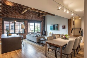 Un espace de vie moderne avec un mur en briques, de grandes fenêtres, une cheminée et un coin repas.
