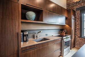 Una cocina moderna con armarios de madera, horno empotrado y cafetera.