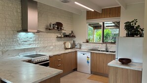A modern kitchen with marble countertops, wooden cabinets, and a built-in dishwasher.