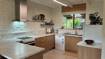 Een moderne keuken met marmeren aanrechtbladen, houten keukenkastjes en een ingebouwde vaatwasser.