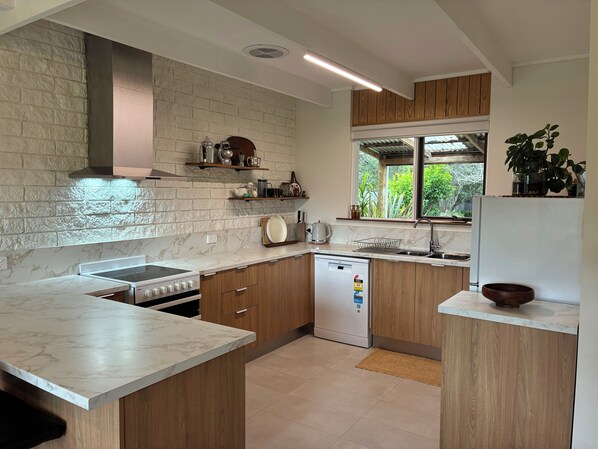 Una cocina moderna con encimeras de mármol, armarios de madera y lavavajillas integrado.