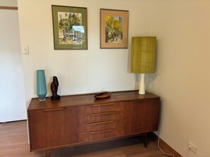 A wooden cabinet with drawers and a vase, two framed paintings, and a lamp on a table.