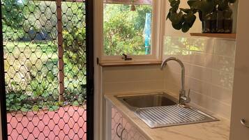 A kitchen with a built-in washing machine, a sink, and a window overlooking a garden.