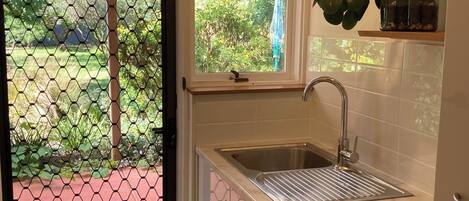 Eine Küche mit Waschmaschine, Spüle und Fenster mit Blick auf einen Garten.