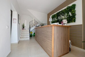 Una zona de recepció amb un taulell de fusta, una escala i un cartell fixat a la paret.