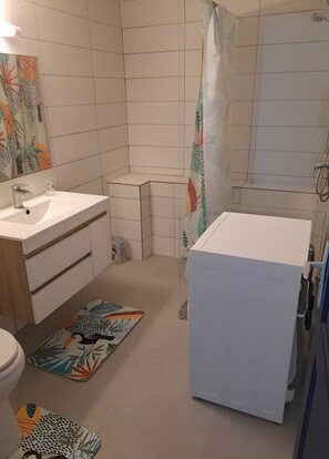 Een badkamer met een wit wastafelmeubel, toilet, douche en een bad.