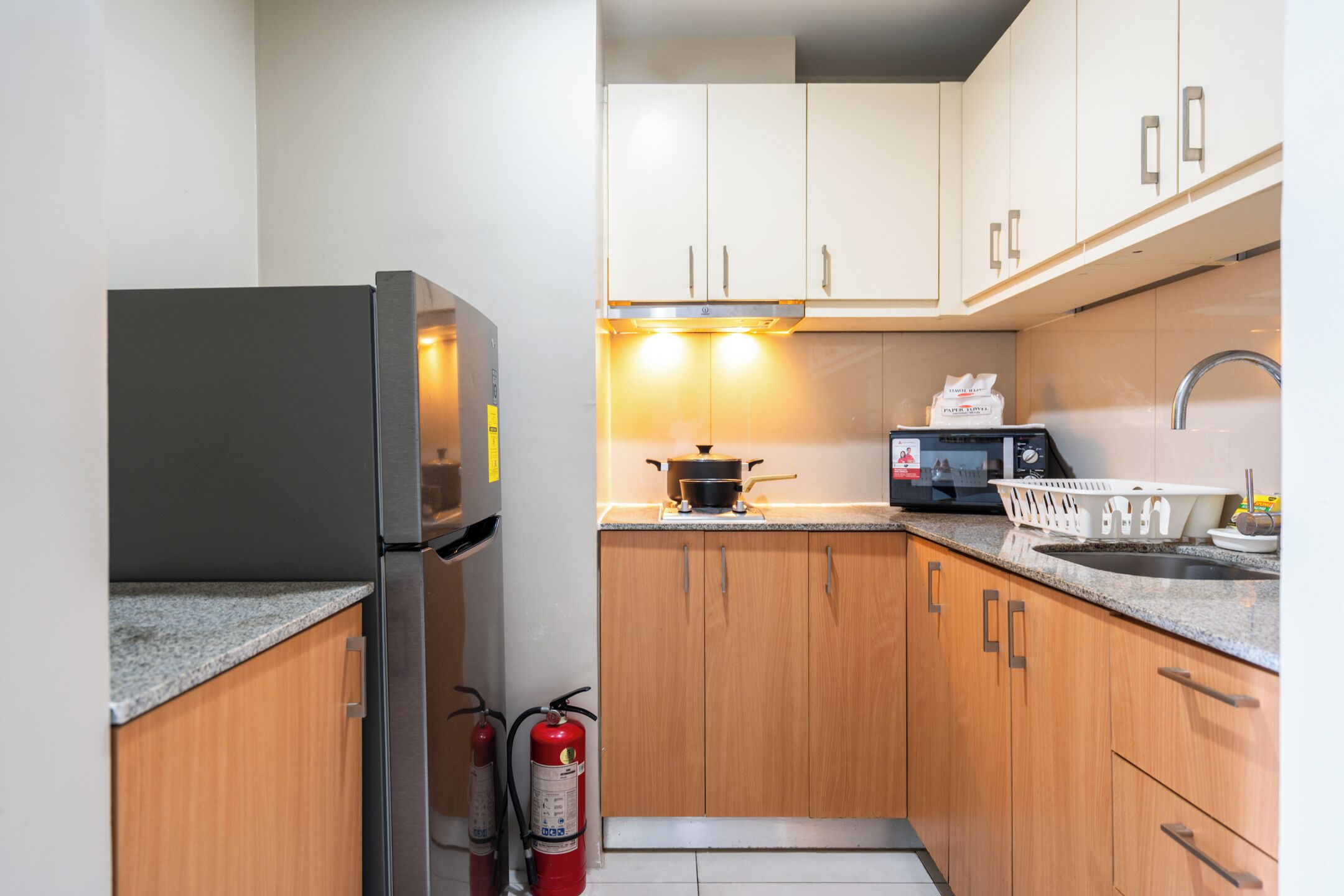 A compact kitchen with a refrigerator, microwave, stove, and wooden cabinets.